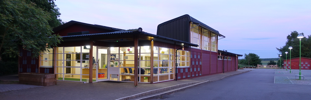 Front of The Eco Hub at dusk with the lights on inside