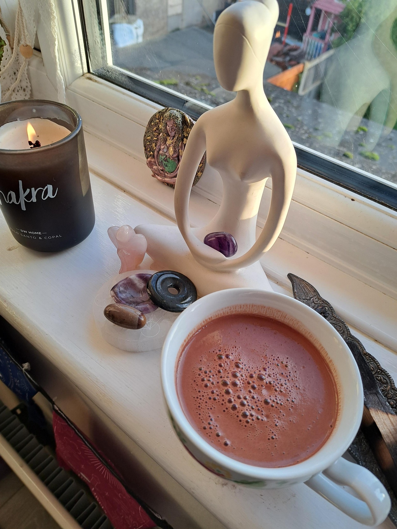 Image of yoga statue, candle and cup of hot chocolate.