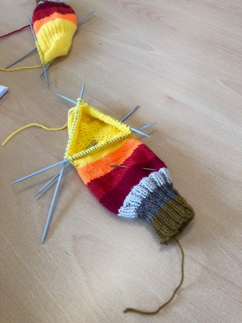 Colourful knitting on its needles