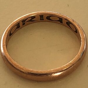 photo of a gold wedding ring with engraving inside it.