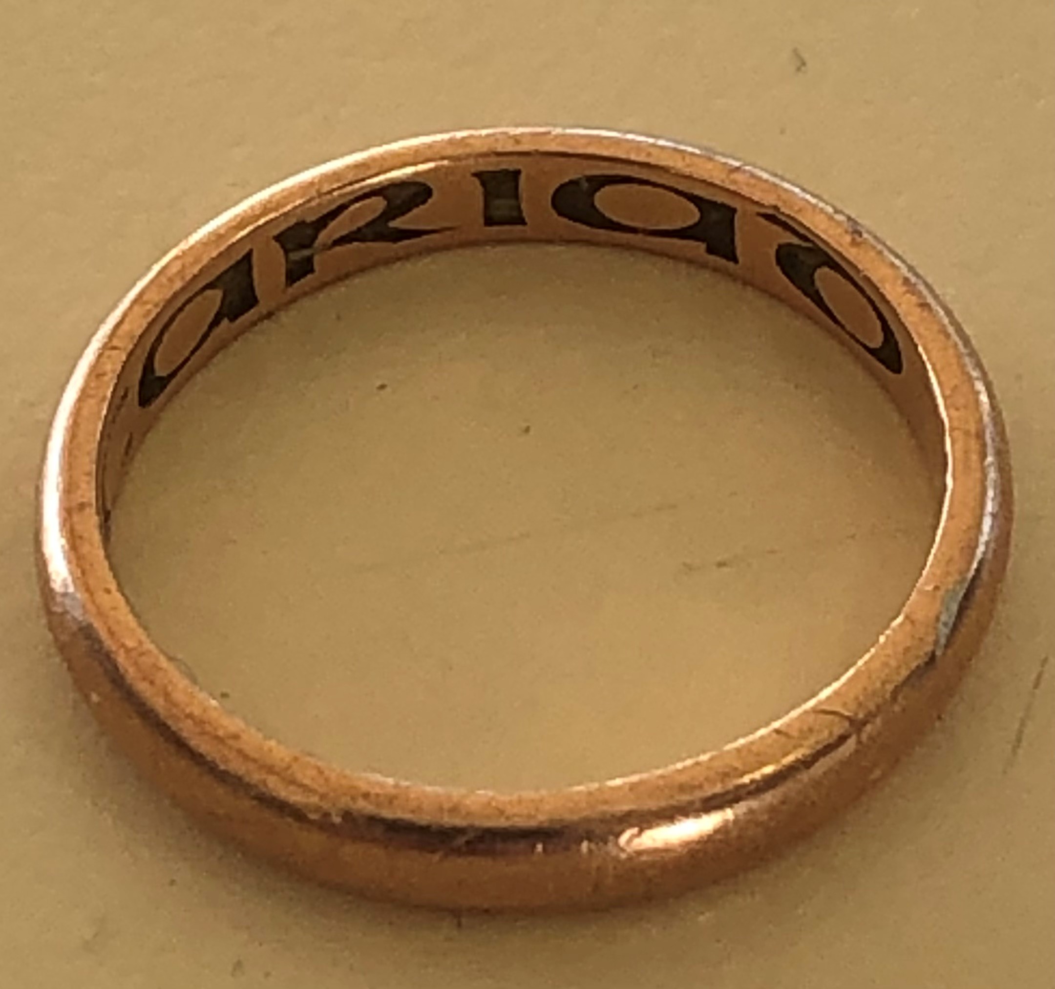 photo of a gold wedding ring with engraving inside it.